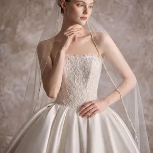 Elegante velo da sposa e abito da sposa in pizzo con dettagli di perline cucite a mano.