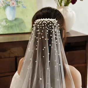Details van de witte bruidssluier met verspreide parels en kam, elegante achteraanzicht.