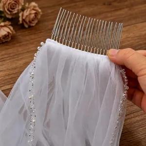 Detail shot of bridal veil comb featuring handmade rhinestones and pearls on white tulle mesh.