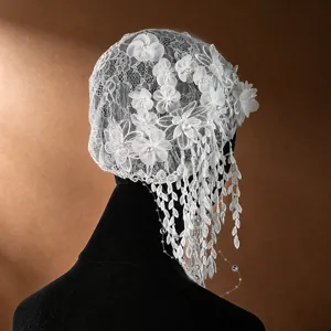 Detailed view of vintage white bridal lace cap with 3d fabric flowers, pearls and tassel design.