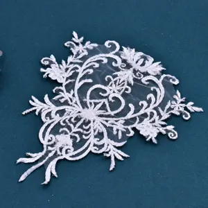 Detailopname van witte kralen kanten borduurwerk applicatie met strass-steentjes en fijne details.