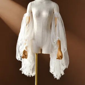 Close-up detail of sheer white tulle ruffled detachable bridal sleeves, delicate mesh design.