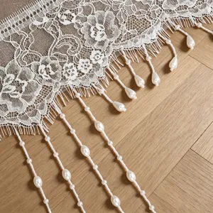 Gedetailleerd overzicht van witte kanten bruidssluier rand met elegante parelkwastjes franje.