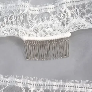 Exquisite bridal lace veil detail featuring a metal comb and delicate white eyelash lace edge.