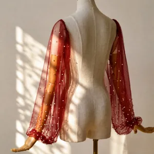 Detail showcase of sheer burgundy mesh sleeves featuring delicate white faux pearls design.