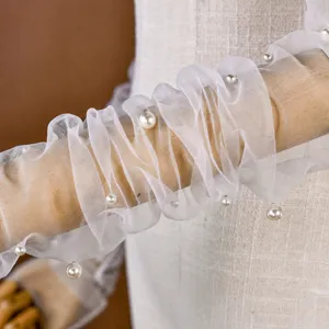 Detail des weißen Mesh-Brauthandschuhs, eleganter transparenter Tüllärmel mit zarten Perlen.