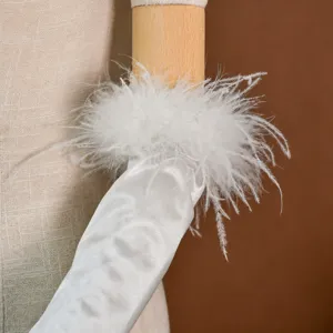 Primo piano di guanti da sposa in satin bianco con bordo in piume per abito nuziale.