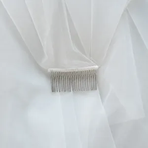 Bruidssluier detail toont fijne metalen kamtanden en elegante zachte witte tule.