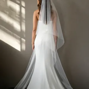 Gedetailleerd achteraanzicht van een klassieke witte bruidsjurk met een dubbele tullen sluier.