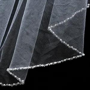 Gros plan détail du voile de mariée blanc avec bordure perlée de perles et de cristaux.