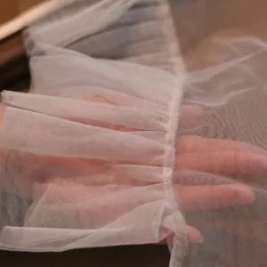 Vue détaillée de gants de mariée en tulle blanc avec volants délicats et tissu transparent.