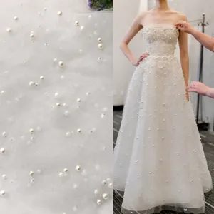 White tulle mesh fabric adorned with pearls and beads, ideal for bridal wedding dress sewing.