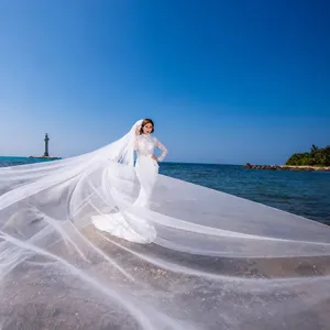 Stunning long bridal wedding veil scene on the beach, featuring sheer mesh fabric blowing in wind.