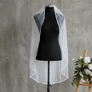 Vue détaillée de l'élégant voile de mariée monocouche avec bord perlé et peigne délicat.