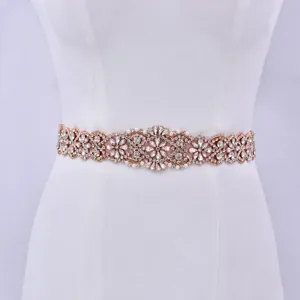 Primo piano dettagliato di una splendida cintura da sposa in strass oro rosa su abito bianco.