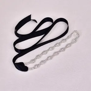 Close-up of bridal rhinestone belt with black ribbon, elegant wedding dress accessory detail.