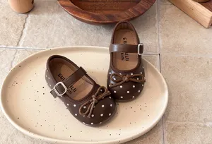 Detailed view of brown polka-dot Mary Jane shoes for kids, featuring soft soles and cute bows.