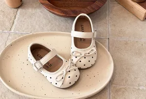 Kids white polka dot mary jane flat shoes with cute bow detail and soft sole for toddler girls.
