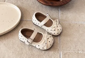Close-up of cute beige polka dot girls Mary Jane shoes with lovely bow and strap detail.