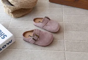 Detailed view of pink suede slip-on children clogs with metal buckle and soft sole.