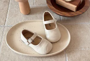 Charming detail view of classic white children Mary Jane flat shoes with soft sole and buckle.