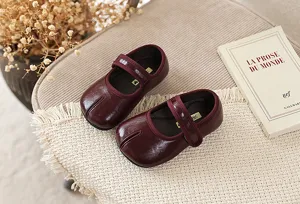 Close-up detail van bordeauxrode Mary Jane kinderschoenen met gespleten teen in retro stijl.