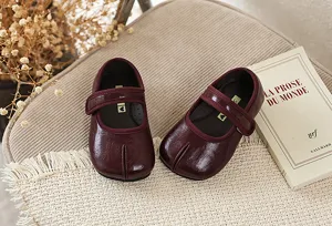 Gedetailleerd overzicht van donkerrode leren kinderschoenen met gespleten neus, chic.