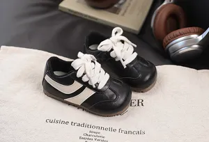 Detail view of black and white children retro sneakers with thick white laces on fabric.
