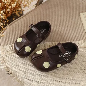 Detail van bruine Mary Jane schoenen met gespleten neus, groene stippen en gespbandje.