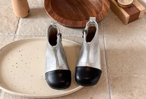 Detailansicht modischer zweifarbiger Mädchen-Stiefeletten mit weicher Sohle und Metallic.