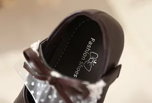 Vista detallada de los zapatos de princesa de cuero marrones para niñas con un lazo.