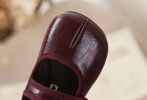 Detailopname van donkerrode leren schoenen met gespleten teen en klassieke retro stijl.