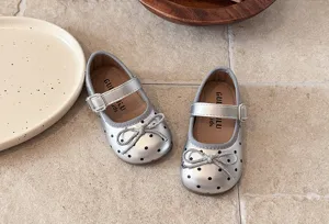 Close-up detail of French style toddler girls silver polka dot Mary Jane shoes soft sole.