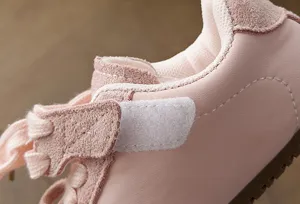 Vista de detalles de zapatillas infantiles en rosa, piel suave y cierre de velcro.