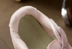 Vista detallada del forro interior rosa y la suela suave de las zapatillas infantiles.