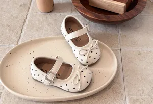 Detail view of white polka dot Mary Jane toddler shoes with a cute bow and strap.