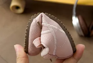Detalle flexible de zapatillas deportivas infantiles con suela blanda y diseño rosa elegante.