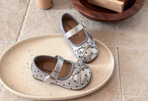 Silver polka dot girls Mary Jane shoes detailed close up, soft sole design with cute bow.