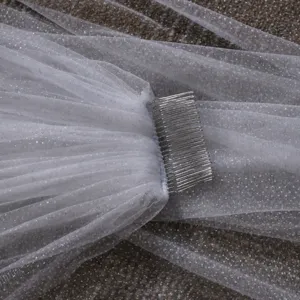 Primo piano dettagliato del velo da sposa in tulle bianco brillante con pettorina in metallo.