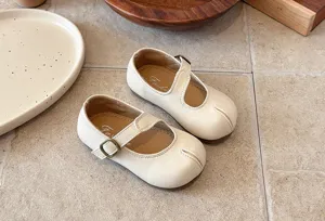 Detalle de zapatos Mary Jane beige para niñas pequeñas con hebilla y suela blanda, estilo retro.