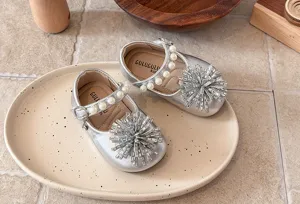 Detailed shot of silver toddler princess shoes with pearl straps and rhinestone flower decor.