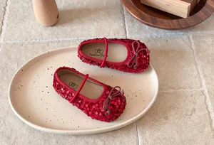 Gros plan de chaussures rouges à paillettes pour bébés avec nœud délicat et semelle souple.