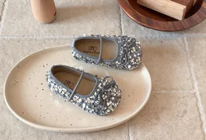 Détail de chaussures plates Mary Jane pour filles en sequins argentés brillants avec nœud.