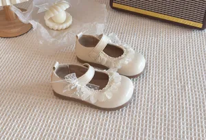 Dettagli di scarpe Mary Jane bianco sporco da bambina con delicate ruches in pizzo morbido.