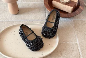 Détail de chaussures plates à paillettes noires pour filles avec design scintillant et nœud.