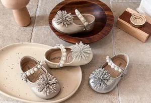 Detail shot of toddler girl princess leather shoes with pearl strap and crystal toe decor.