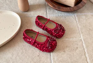 Gros plan détaillé des chaussures Mary Jane rouges à paillettes pour filles avec joli nœud.