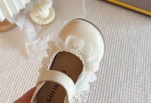 Dettaglio scarpe principessa bambina avorio carine, dolci fiori in pizzo, suola morbida.