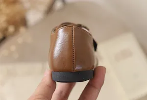 Detalle de zapatos de cuero marrón para niñas, tacón Mary Jane con suela blanda, elegante.
