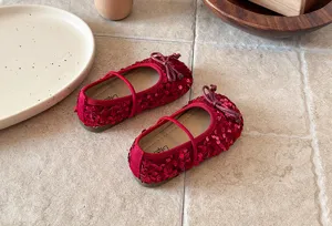 Détail de chaussures de princesse à sequins rouges pour filles, semelle souple plate avec nœud.